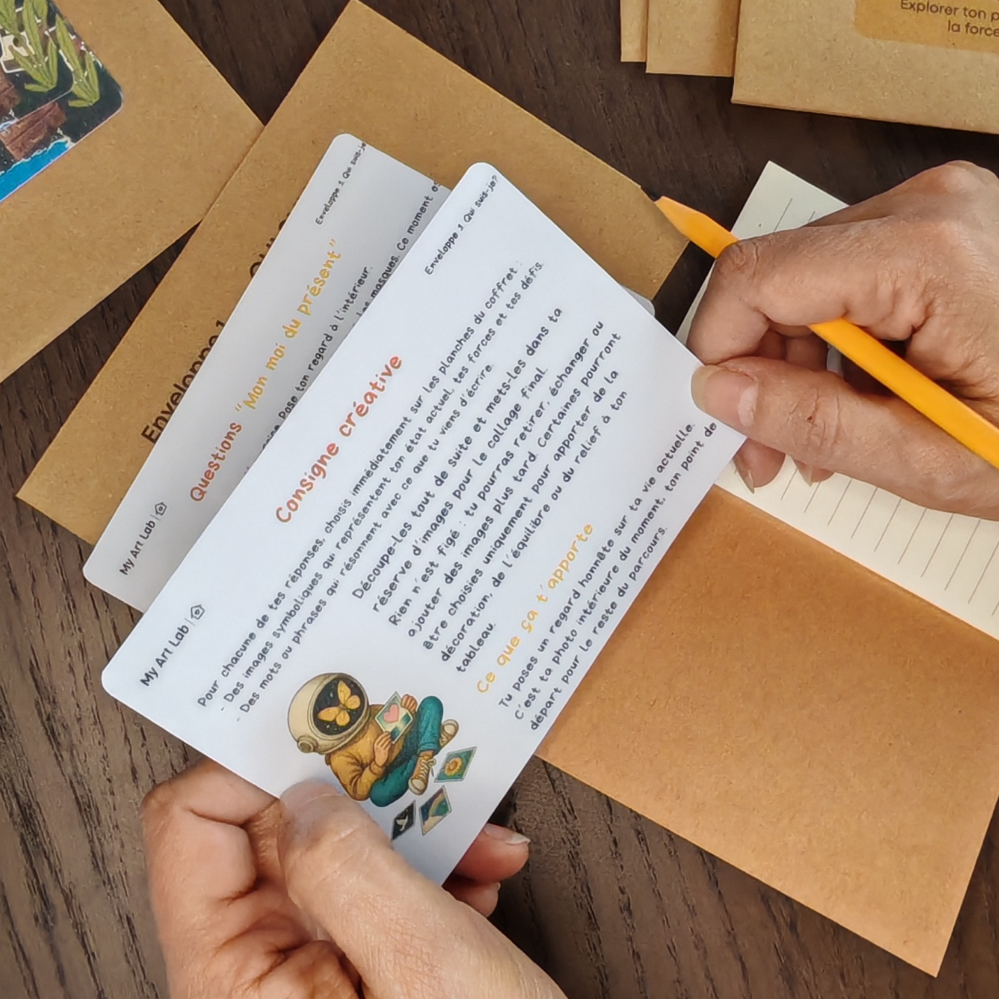Personne répondant à des questions guidées My Art Lab avec cartes et carnet pour un collage introspectif